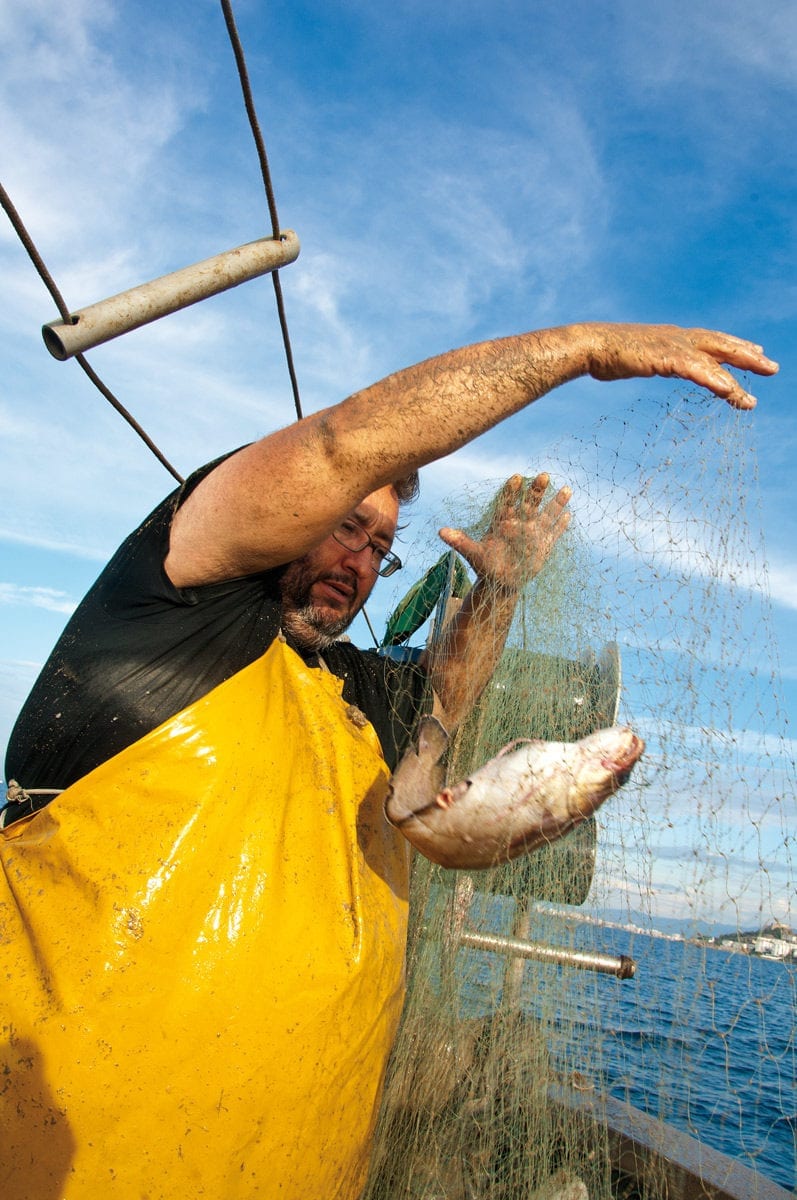 Fischer holt Fisch aus dem Netz