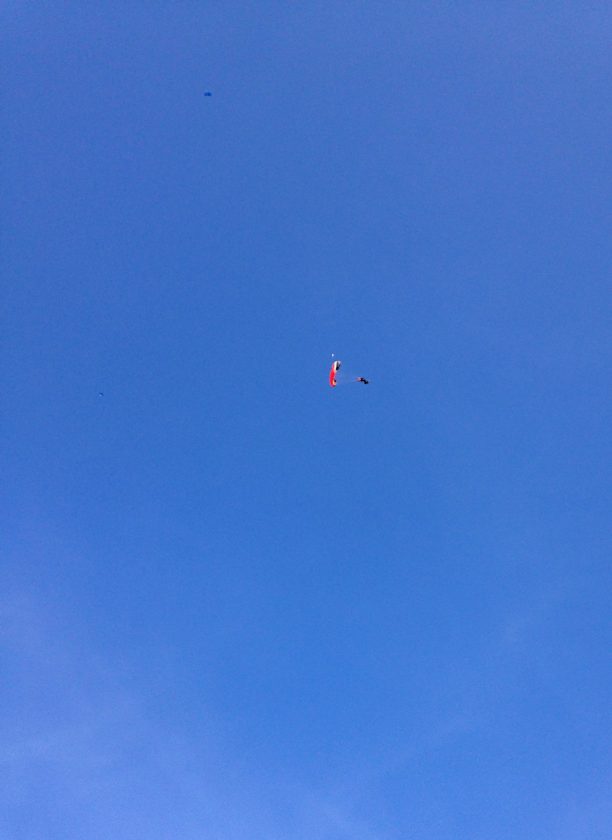 Fallschirmspringer hoch oben am Himmel.